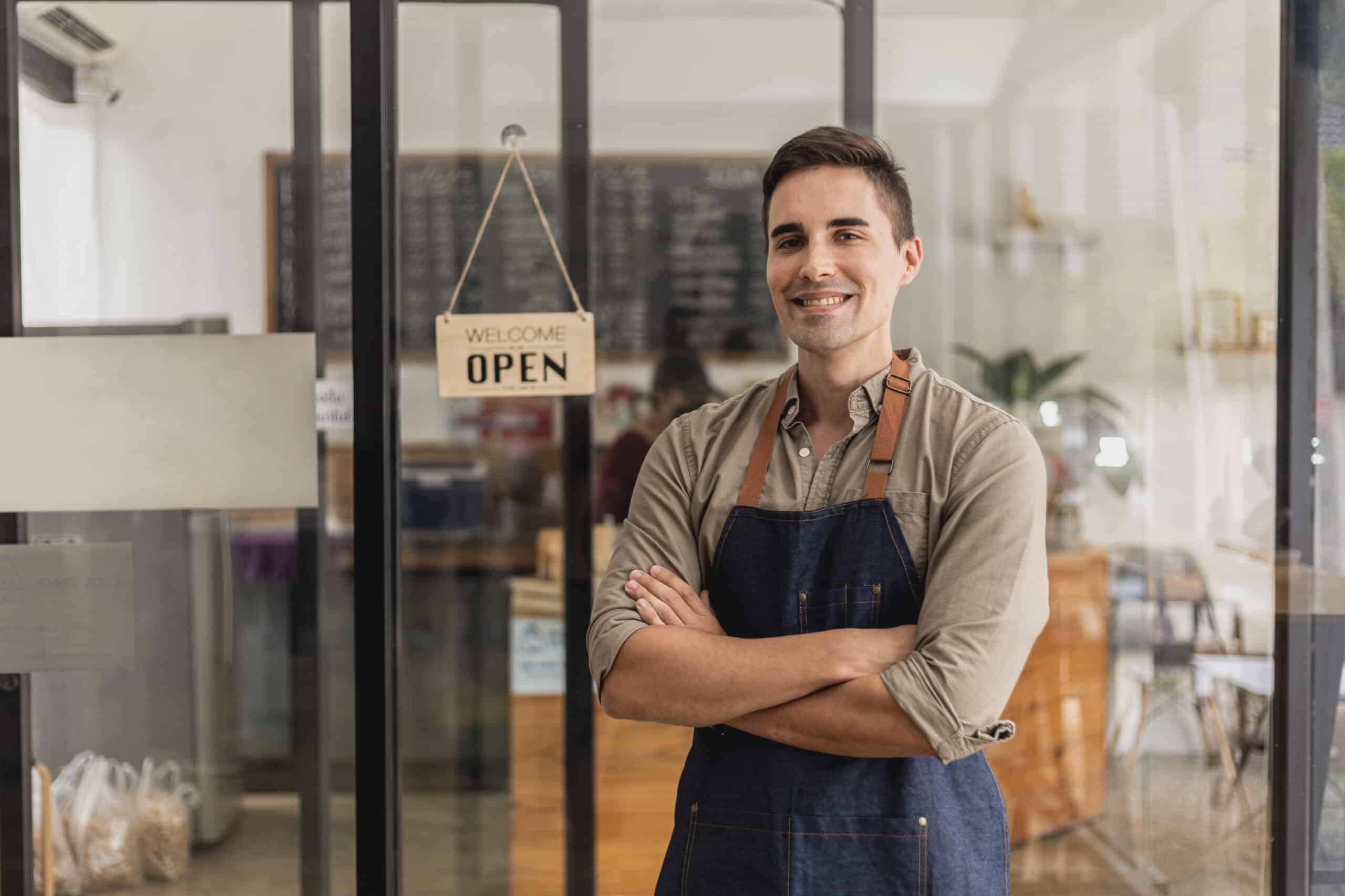 A proud small business owner standing beside his 'Grand Opening' sign, showcasing how WordPress has empowered his online presence and success